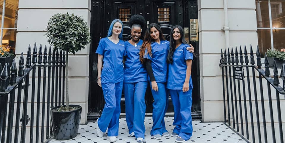 Four nurses in blue scrubs outside a Georgian clinic entrance for EMface facial toning in Dublin